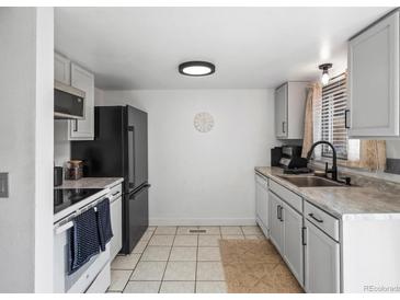 Modern kitchen with black appliances, gray cabinets, tile floors, and natural light at 12993 W 20Th Ave, Golden, CO 80401