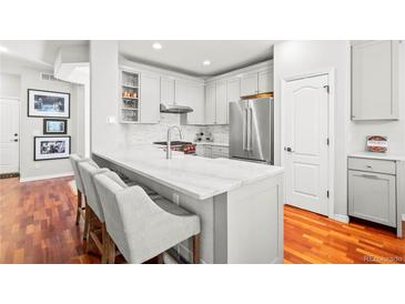 Bright, white kitchen with marble counters, stainless appliances and a breakfast bar for seating at 6135 S Paris St, Englewood, CO 80111