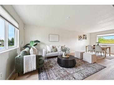 Bright living room featuring modern furnishings, a patterned rug, and light wood flooring at 9740 W 104Th Dr, Westminster, CO 80021