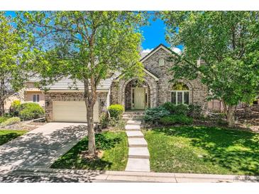 Charming brick home with an arched entry, well-manicured lawn, and mature trees at 85 Silver Fox Dr, Greenwood Village, CO 80121