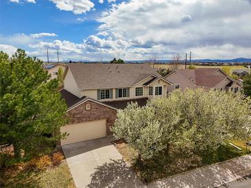 Charming two-story home with a brick facade and a well-manicured front yard and blue skies at 5934 Kingsfield St, Castle Rock, CO 80104