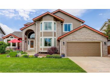 Charming two-story home boasts a brick facade, well-manicured lawn, and an attached two-car garage at 9537 Chesapeake St, Highlands Ranch, CO 80126
