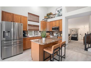 Well-lit kitchen featuring stainless steel appliances, granite countertops, an island with seating, and abundant cabinet space at 15776 E 107Th Way, Commerce City, CO 80022
