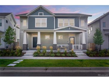 Two-story townhome with gray siding, front porch, and landscaping at 6347 N Emporia St, Denver, CO 80238