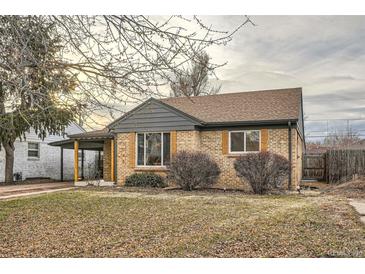 Charming brick home featuring updated gray trim, a covered porch, and mature landscaping at 3045 Kearny Street, Denver, CO 80207