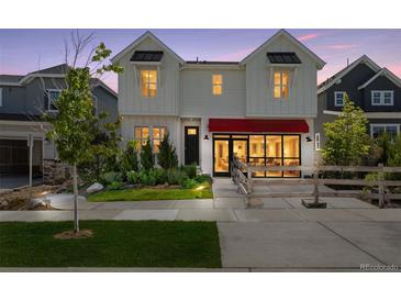 Charming two-story home with a red awning, beautiful landscaping, and a welcoming front entrance at 13326 Blue Amber Ct, Parker, CO 80134