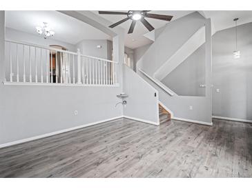 An open living room features hard surface floors, a ceiling fan and a staircase at 1473 Red Cliff Way, Castle Rock, CO 80109
