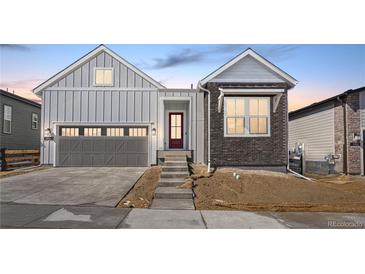 Charming home with gray siding, brick accents, and a two-car garage, enhanced by a red entry door at 6675 Fawn Path Ln, Castle Pines, CO 80108