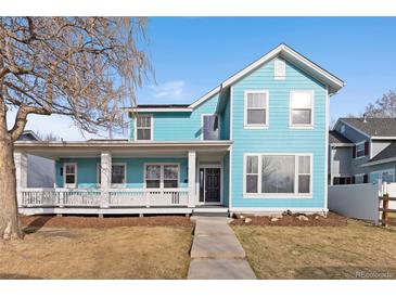 Charming blue two-story home featuring a spacious front porch with white pillars and ample natural light at 5129 Mt Arapaho Cir, Frederick, CO 80504