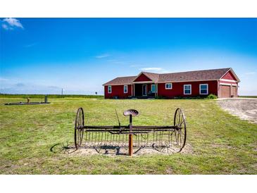 Charming red home on a sprawling green lawn under a clear blue sky at 46122 County Road 53, Bennett, CO 80102