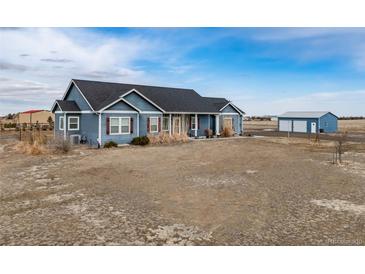 Ranch-style home with a blue exterior, dark roof, and a detached garage on a spacious lot at 253 E 8Th Ave, Byers, CO 80103
