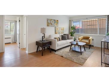 Bright living room featuring hardwood floors, white sofa, stylish decor, and natural light through the windows at 1454 Jersey St # 2, Denver, CO 80220