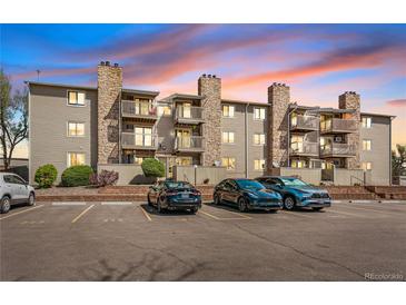 Exterior view of a multi-story apartment building featuring stone accents and balconies at sunset at 381 S Ames St # E305, Lakewood, CO 80226