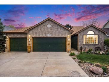 Charming brick home featuring a three-car garage and a well-maintained front yard with a concrete driveway at 2190 Coyote Creek Dr, Fort Lupton, CO 80621