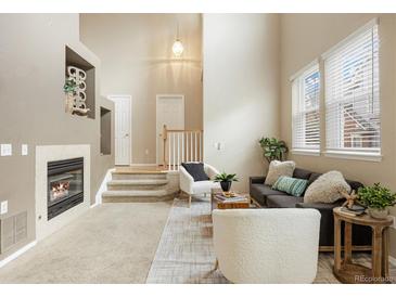 Bright living room showcasing a fireplace, staircase, and ample natural light from large windows at 6702 S Winnipeg Cir # 101, Aurora, CO 80016