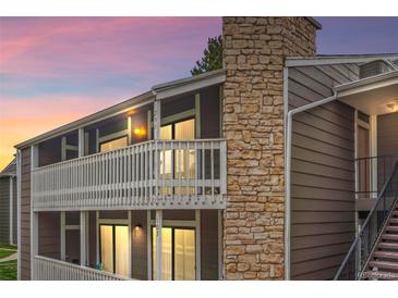 Condo exterior with stone accents, white railing, and well-lit windows at dusk at 18133 E Kentucky Ave # 203, Aurora, CO 80017