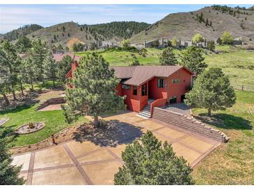 Red home exterior with a large driveway and trees, nestled in a scenic mountain setting at 10991 Expedition, Littleton, CO 80125
