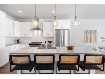Bright kitchen features an island with bar seating and modern stainless steel appliances at 2952 S Delaware St, Englewood, CO 80110