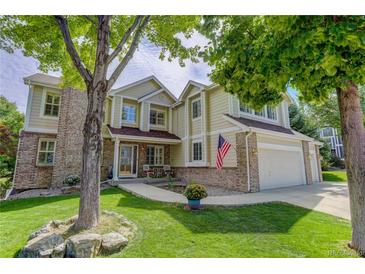 Inviting two-story home with manicured lawn, brick accents, and charming front porch and American flag at 10032 Astoria Ct, Lone Tree, CO 80124