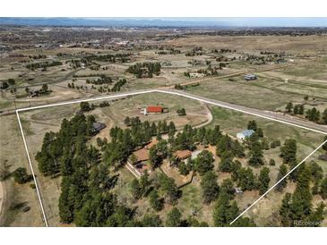 Expansive aerial view of a beautiful property with mature trees, horse facilities, and a charming home in a serene setting at 7076 Inspiration Dr, Parker, CO 80138