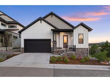 Charming two-story home with a black two car garage and beautifully landscaped front yard at sunset at 7022 Homeplace St, Castle Rock, CO 80108