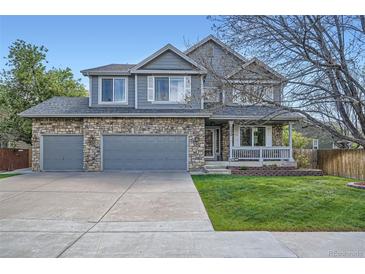 Charming two-story home featuring a stone facade, attached garage, and a covered porch, complemented by a well-maintained lawn at 13330 York Way, Thornton, CO 80241