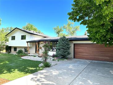 Beautifully landscaped front yard leads to this charming home with a wooden garage door and brick accents at 11569 W 27Th Ave, Lakewood, CO 80215