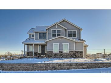 Two-story house with gray siding, stone accents, and a snowy front yard at 9880 E 160Th Pl, Brighton, CO 80602