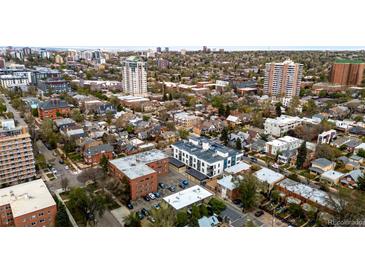 A vibrant aerial view of a residential neighborhood, showcasing a mix of houses, buildings, trees, and the city skyline at 70 N Grant St # 10, Denver, CO 80203