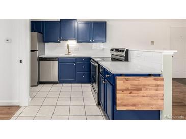 This renovated kitchen features stainless steel appliances, white countertops and subway tile, and stylish navy blue cabinetry at 70 N Grant St # 10, Denver, CO 80203