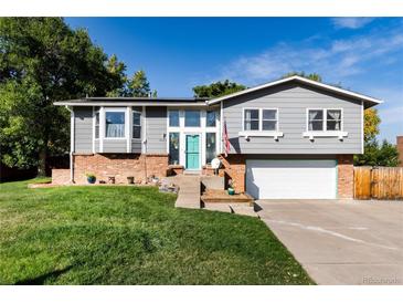 Charming home featuring a manicured lawn, brick accents, and a striking turquoise front door at 8063 S Otis Ct, Littleton, CO 80128