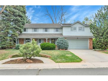 Charming two-story home featuring a well-manicured lawn, mature trees, and an attached two-car garage at 7058 S Madison Way, Centennial, CO 80122