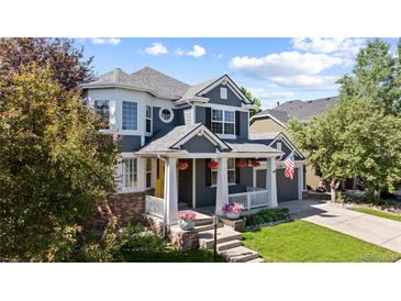 Charming two-story home with a well-maintained lawn, inviting porch, and beautiful, mature landscaping at 16376 Stonefeld Pl, Parker, CO 80134