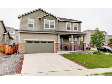 Two-story home with a two car garage, landscaped yard, and a covered porch at 9250 Rifle St, Commerce City, CO 80022