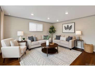 Bright living room features hardwood floors, neutral paint, two sofas, arm chair, coffee table, and recessed lighting at 1996 S Dexter St, Denver, CO 80222
