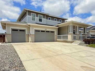 Charming two-story home featuring a three car garage, covered porch and concrete driveway at 3029 Merlin Dr, Brighton, CO 80601