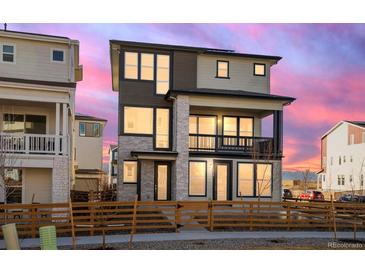 Stunning two-story home with a stone facade, second story balcony, and beautiful landscaping, at sunset at 928 Farrier Ln, Lafayette, CO 80026