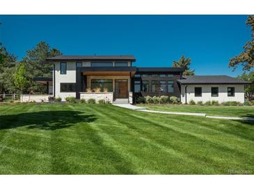 Stunning modern home showcasing a sprawling green lawn, stone accents, and a walkway leading to the inviting front entrance at 17326 W 57Th Ave, Golden, CO 80403