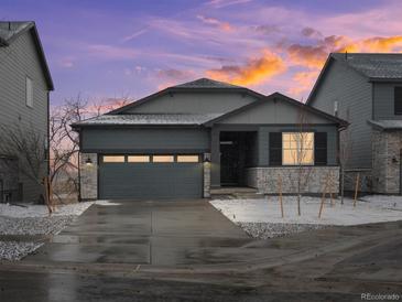 Charming single-Gathering home featuring stone accents, a gray two-car garage, and a beautifully landscaped yard with a colorful sunset at 1947 S Coolidge Way, Aurora, CO 80018