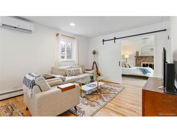 Bright living room featuring a comfortable sofa, stylish rug, and sliding barn door to bedroom at 5115 Bryant St, Denver, CO 80221