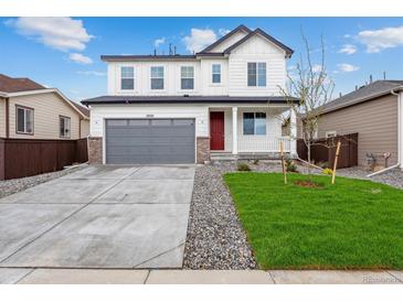 Beautiful two-story home featuring an attached two-car garage, well-manicured lawn, and charming red door at 19120 E 96Th Pl, Commerce City, CO 80022