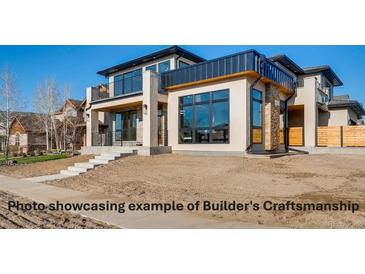 Stunning two-story home featuring a modern design with large windows, stone accents, and a stylish balcony at 1055 Greens Pl, Erie, CO 80516