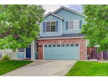 Charming two-story home featuring a brick facade, blue siding, a well-manicured lawn and mature shade trees at 15828 Greenstone Ln, Parker, CO 80134