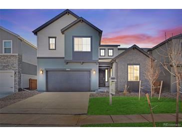 Two-story home featuring a two-car garage, gray siding and a well-maintained lawn at 9982 Wheeling St, Commerce City, CO 80022