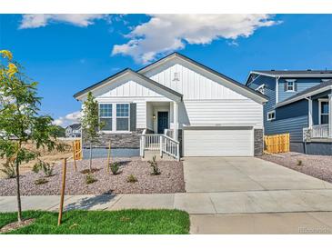 Charming white home featuring a two-car garage and nicely landscaped front yard at 13575 E 110Th Ln, Commerce City, CO 80022