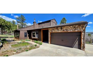 Charming exterior view of home featuring a two-car garage and lush landscaping at 18170 Forest View Rd, Monument, CO 80132