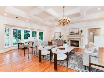 Bright living room features hardwood floors, coffered ceilings, large windows, and a fireplace with stone mantel at 4800 S Franklin St, Cherry Hills Village, CO 80113