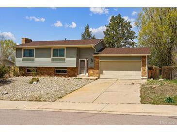 Charming split-level home with a two-car garage, well-maintained lawn, and a classic brick and siding facade at 219 Douglas Fir Ave, Castle Rock, CO 80104