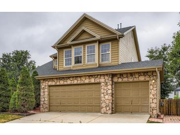 Two car garage with stone accents, neutral doors and dark roof at 5553 Jasper St, Denver, CO 80239