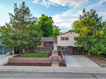 Charming split-level home featuring a brick facade, lush landscaping, and inviting curb appeal at 9123 W Arbor Ave, Littleton, CO 80123
